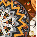 A close up on the outer folded points of the table topper, demonstrating fabric colors and details. Coordinating décor peeks into frame from the upper right corner.