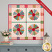 The completed Dresden Wall Hanging, colored in lovely pink, green, orange, teal, red, and purple calico fabrics from the Gentler Times collection. The project is hung on a gray wall and staged with coordinating gentle décor.