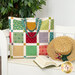 The completed Magic Charm Pack Tote in calico prints from the Gentler Times collection by Riley Blake Designs, staged on a white bench with coordinating summer props and décor.