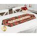 The completed Easy Striped Table Runner colored in floral red, cream, and black fabrics from the Cardinal Celebration collection by Timeless Treasures Fabrics, staged on a white table.