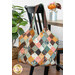 The completed Mondo Bag colored in rich fall fabrics from the Acorn Hollow collection by Moda, staged on a black chair and table.