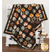 A shot of the Leaf Pile quilt colored in autumn themed fabrics from the Acorn Hollow collection and artfully draped over a white armoire, staged with coordinating decor.