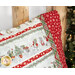 A slightly angled shot of the top right of the pillowcase on the wood log bed, demonstrating fabric print and color details. A decorated Christmas tree peeks into frame from the right side.