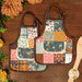 The two completed hot pads colored in warm fall fabrics from the Acorn Hollow collection, staged on a dark wooden background with coordinating fall decor and a wooden spatula.