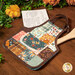 An angled shot of one of the hot pads staged on a wooden table with a recipe card sticking out.