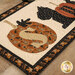 A close up on the first appliqué pumpkin of the runner, showing fabric and topstitching details on the leaf, stem, and 