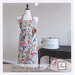 Floral-patterned apron displayed on a mannequin beside a vintage canister, showcasing farm-inspired design.