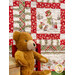 A closer look at the quilt, showcasing a block with mice building a snowman. A decorative teddy bear sits in the lower left corner.