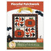Front cover of the Pieceful Patchwork - October pattern, showing the completed wall hanging in cream, orange, and black fabrics, staged with coordinating Halloween decor.