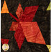A super close up on a red pieced leaf set against a contrasting black-brown background, demonstrating fabric color and print details.