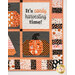 A close up on the quilt, demonstrating fabric color and print details on a pieced pumpkin block and a white block with appliqué text that reads, 