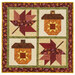 The completed Pieceful Patchwork - November wall hanging, a square project with two patchwork acorns and leaves in autumn themed fabrics, isolated on a white background.
