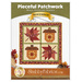 Front cover of the pattern showing the completed Pieceful Patchwork - November wall hanging, a square project with two patchwork acorns and leaves in autumn themed fabrics, staged on a white wall with coordinating decor.