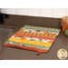 A shot of the drying mat colored in soft autumn fabrics, staged on a kitchen counter. Coordinating decor peeks into frame from the right side.