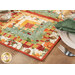 A shot of the log cabin patchwork of the runner, demonstrating vibrant fabric colors and prints as well as top quilting details; coordinating flowers and table ware peek into frame.