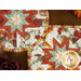 A stylized close up on the two hot pads on a wooden table. Leaves and coordinating florals peek into frame from the edges.