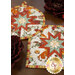 A stylized close up on the two hot pads on a wooden table. Dark florals peek into frame from the corners.