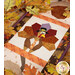 A close up on the middle turkey block, framed by decorative fall leaves on a wooden tabletop.