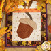 A close up on an acorn block, framed by decorative fall leaves on a wooden tabletop.