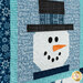 An angled close up on one of the snowman blocks, showing details on his hat and appliqué face as well as top quilting details.
