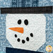 A super close up on one of the snowman blocks, showing details on his hat and appliqué face as well as top quilting details.