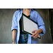 A person in a striped shirt holds a drawing tablet against their body, standing in front of a neutral background.