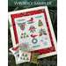 A framed winter-themed cross-stitch sampler with red accents, featuring cardinals, pinecones, and snowflakes.