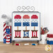 The completed July spool, three popsicles in patriotic colors, hung on a craft holder and staged on a wooden table with coordinating spools and decor.