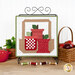 The completed September spool, three red apple themed spools, hung on a craft holder and staged on a wooden table with coordinating spools and decor.