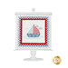 The completed cross stitch project for July's Needle Minder of the Month club, displayed on fabric and painted white frame mount.