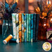 A stack of fabrics included in the Raven's Call collection, with jars and flowers and feathers and thread.