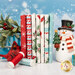 A stack of the fabrics included in the Holly Jolly collection, with snowflakes and a snowman and a present box and mistletoe and a cardinal and thread.