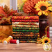 A stack of the fabrics included in the Autumn Cats collection, with flowers and leaves and a cat statue and a jar and thread.
