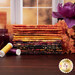 A stack of the fabrics included in the Bali Batiks - Ember Glow FQ Bundle, with a window and jars and candles and flowers and thread.