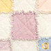 A super close up on one of the quilt blocks, demonstrating details on the fabric, top quilting, and the frayed rag seams of the project.