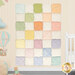 The completed Layer Cake Rag Quilt colored in soft pastel fabrics from the Little Lambies collection by Maywood Studio, hung on a light yellow wall and staged with coordinating toys and decor.
