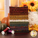 A stack of the fabrics included in the Bountiful Blessings collection, with sunflowers and a vase and leaves and a window and pumpkins and thread.
