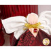Detail shot of the angel, highlighting the metallic effect of the wings and showing the angel's metallic gold bow with a deep red charm that resembles a garnet in a golden setting.