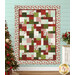 The completed Easy as ABC quilt in red, green, aqua, and cream fabrics from the Make it Merry collection by Marcus Fabrics, hung on an aqua wall and staged with coordinating flowers and furniture.