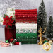 A stack of the fabrics included in the Merry Mix Fat Quarter Bundle, with trees and snow and a jar and flowers and thread and baubles and a deer and candycanes.