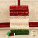 A stack of the fabrics included in the Christmastime collection, with thread and the included panel.