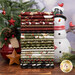 A stack of the fabrics included in the Northern Christmas collection, with a tree and star ornaments and a bell and a snowman and pine branches