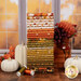 A stack of the fabrics included in the Bountiful collection, with pumpkins and flowers and a jar and a window and thread.