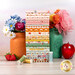 A stack of the fabics included in the Cotton Nook collection, with flowers and jars and a apple and strawberries and thread.