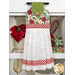 The completed hanging towel staged on a kitchen drawer, colored in white, green, and red fabrics from the Make it Merry collection. Coordinating red decor peeks in from behind the towel.