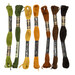 A shot of seven skeins of embroidery floss in green, yellow, orange, and brown, isolated on a white background.