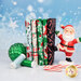 A stack of the fabrics included in the Dancing Santas collection, with snowflakes and an ornaments and a candycane and a ceramic and felt Santa and thread.