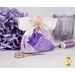 The completed February Birthstone Angel with an amethyst palette, white wings, and a silver bow and light purple charm beside coordinating decor and notions.