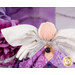 Detail shot of the angel, highlighting the metallic effect of the wings and the angel's metallic silver bow featuring a deep purple charm that resembles an alexandrite in a golden setting.