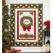 The completed Ribbon Border Panel Quilt colored in red, green, cream, and gold metallic fabrics from the Joyful collection by Timeless Treasures, hung on a white paneled wall and staged with a decorated tree, poinsettia flowers, and presents in coordinating colors.